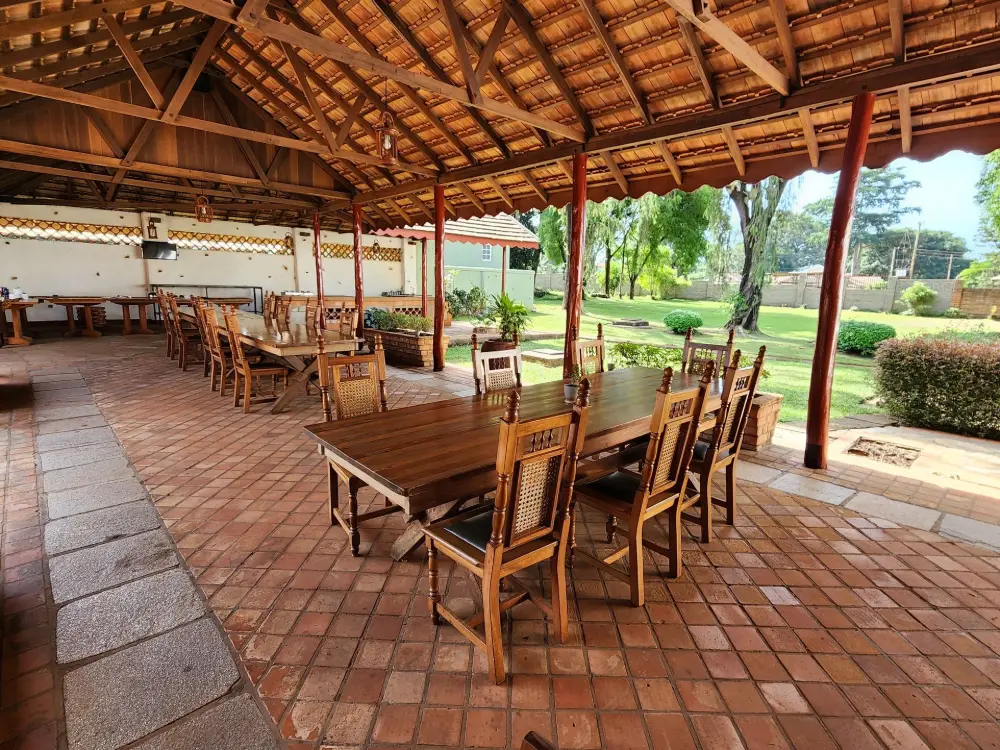 Open-sided thatched dining terrace with rows of wooden tables at Masindi Hotel
