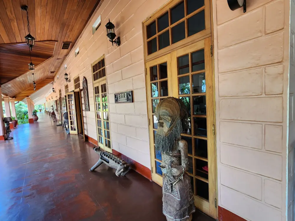 Corridor with a carved wooden statue outside guest rooms at Masindi Hotel