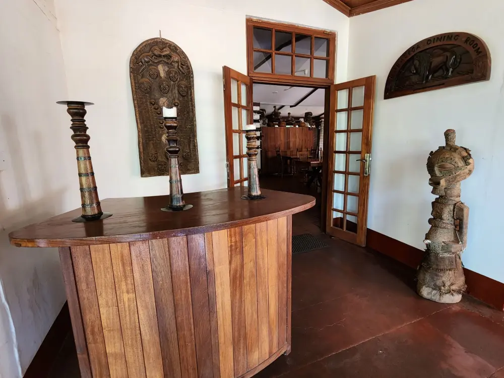 Wooden reception desk decorated with African carvings and sculptures at Masindi Hotel